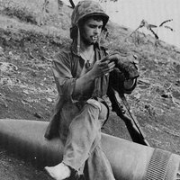 Príslušník námornej pechoty sedí na neexplodovanom delostreleckom granáte ráže 16 palcov. Saipan, 1944.
